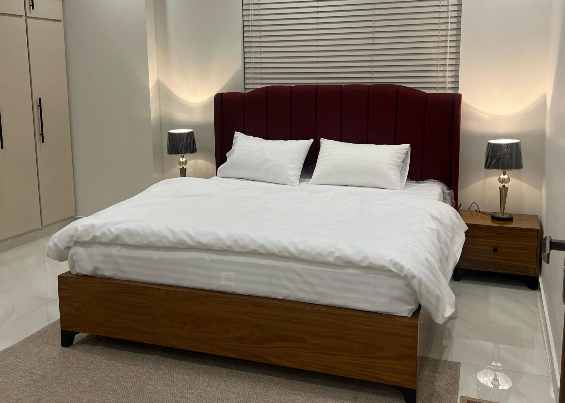 Bedroom with white bedding and a burgundy upholstered headboard